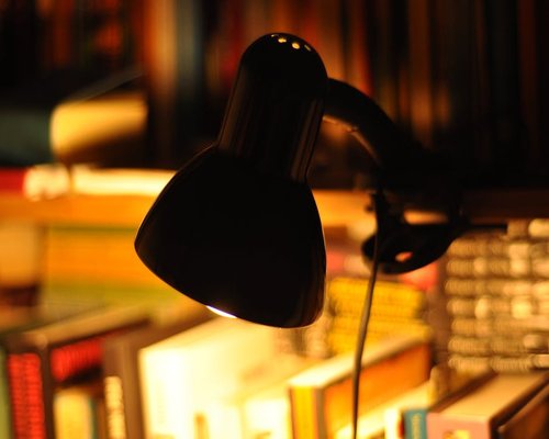 A high contrast macro focus on a physical book and a reading lamp producing clean ambient illumination